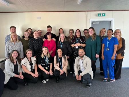 Temporary staffing in two rows, smiling in their office space having been shortlisted for a Nursing Times Workforce Award.