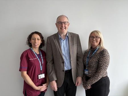 Rebecca Haynes (NET Clinical Nurse Specialist), Mark Pritchard (Consultant Gastroenterologist and NET MDT clinical lead) and Gemma Currie (NET MDT coordinator) stood together smiling against a plain wall.