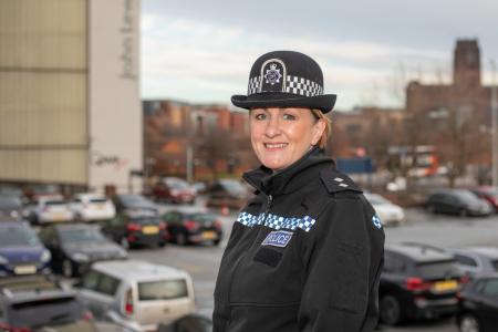 Woman in police uniform against a city backdrop