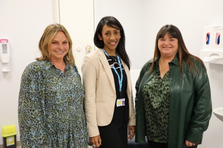 Tina Dutt (Central), Tracey (right) and Jane (left) all stood together smiling ahead of the film premier launch at the Royal Liverpool University Hospital. The room they are all standing in is a consultation room which Jane and Tracey visit for regular check-ups.